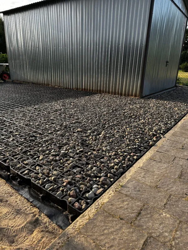 Zastosowanie kratki parkingowej wokół blaszanej szopy ogrodowej