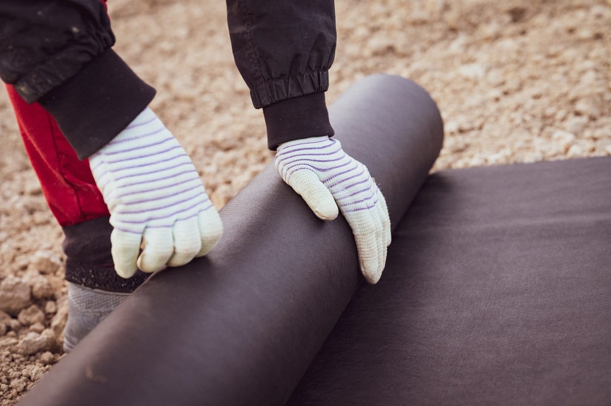 Osoba rozwija rolkę agrowłókniny